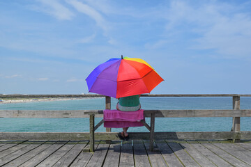 Person sitting under umbrella looking at ocean