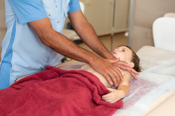 Wellness massage for children. Hands of the masseur close-up. Physiotherapist working with patient...