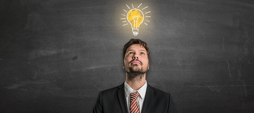 businessman with a lightbulb in front of a blackboard