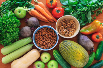 Organic fresh vegetables, almonds and walnuts. Vegan healthy raw food on wooden table background. Top view, flat lay