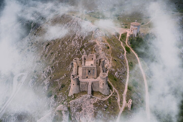 aerial view of the medieval castle of rocca calascio and church of abruzzo shrouded in fog