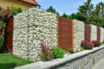 Moderner Sichtschutzzaun abwechselnd aus mit Naturstein gefüllten Gabionen aus verzinktem...