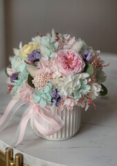 Bouquet with roses, hydrangea and a and lagurus in a tiffany colors. Stabilized flowers in a ceramic vase at home on the dressing table. Interior decor.