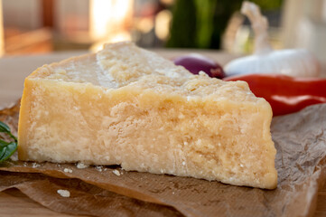 Cheese collection, piece of matured cow cheese pasmesan parmigiano reggiano and Italian houses on background