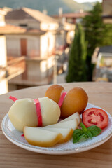 Cheese collection, variety of Italian cow milk cheese scamorza with Italian houses on background