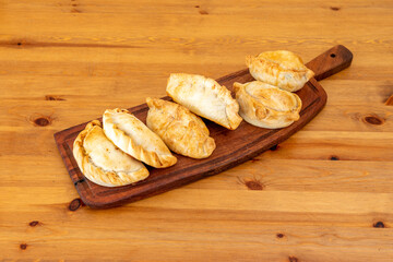 Argentine empanadas stuffed with traditional beef stew with onion and vegetables on wooden board