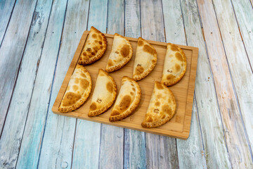 Eight Argentine empanadas of different flavors ready for snack on bamboo wood board