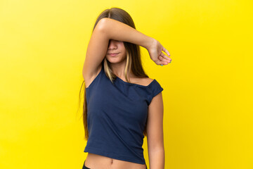 Little caucasian girl isolated on yellow background covering eyes by hands