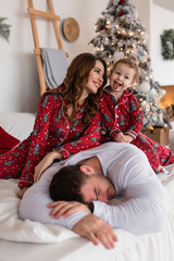 Merry Christmas and Happy Holidays. Happy mom, dad and daughter near the Christmas tree. The morning before Christmas. Close-up portrait of a loving family