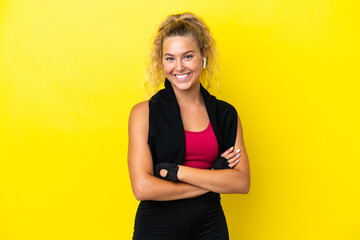 Sport woman with towel isolated on yellow background keeping the arms crossed in frontal position