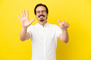 Young caucasian man isolated on yellow background counting six with fingers