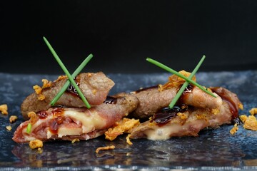 Japanese beef rolls teriyaki filled with cheese served on a grey plate with dark background