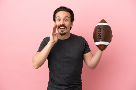 Young caucasian man playing rugby isolated on pink background with surprise and shocked facial expression