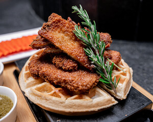 Exquisite waffle with chicken served on a board.