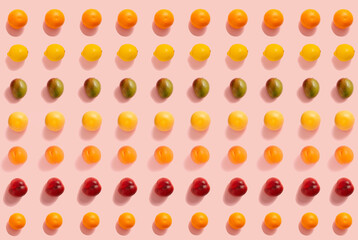 Fruit pattern made of oranges, lemons, mangos, grapefruits, apricots and peaches on the pastel pink background. Minimal flat lay composition.