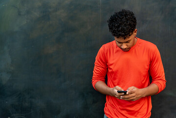 Afro latin young man talking by mobile phone against a wall