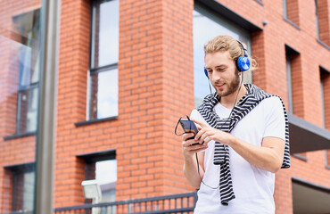 An attractive guy tourist walks around a new city, uses an audio guide.