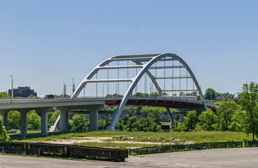 Fototapeta premium Nashville, TN, USA - May 20, 2007: Downtown. Closeup of Korean War Veterans bridge with a few brown empty train wagons nearby under blue sky. Green foliage around.