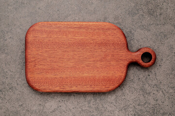Empty vintage wooden cutting board set up on dark concrete background with copy space.