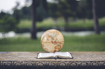 Open Bible and a globe on a bench