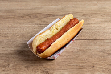 A plain hotdog in a bun on a wooden table