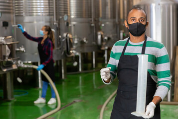 Man in protective mask with beaker in a winery shop