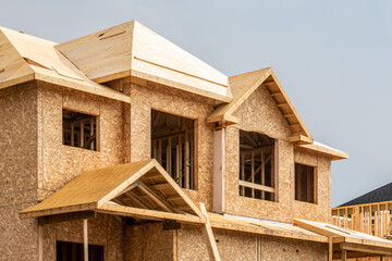 A residential frame house construction project showing the engineered truss roof rafters and...