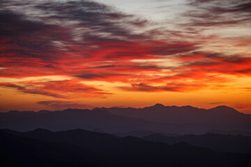 真っ赤な朝焼けの雲が稜線上に流れる