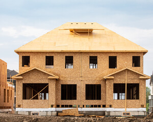 A residential frame house construction project showing the engineered truss roof rafters and...