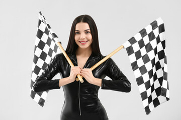 Beautiful young woman with racing flags on light background