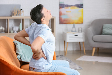 Young man suffering from back pain at home