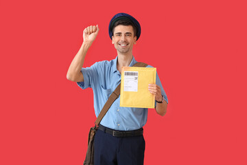 Handsome young postman with letter on color background