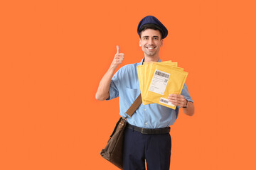 Handsome young postman with letters showing thumb-up on color background
