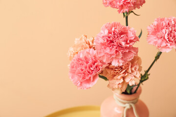 Vase with beautiful carnation flowers on table near color wall