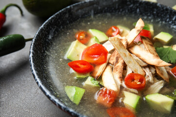 Bowl of tasty Sopa de Lima soup on dark background, closeup