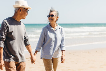 Romantic Senior couple strolling happily along the beach in the warm sunshine. Plan life insurance...