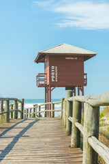 Wooden boardwalk on the beach with lifeguard tower on an empty beach with clear sand and blue sea in southern Brazil. Lifeguard station. Safety concept.