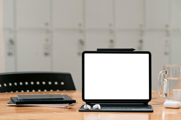 Fototapeta premium Mockup blank screen tablet with magic keyboard on wooden table in locker room.