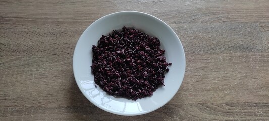 Rice, ryeberries in white plate, on wooden floor, top view.