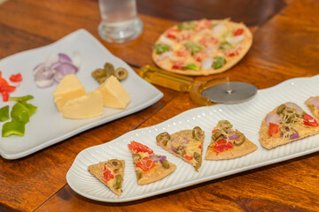 Baked and sliced pizza along with its ingredients served on table
