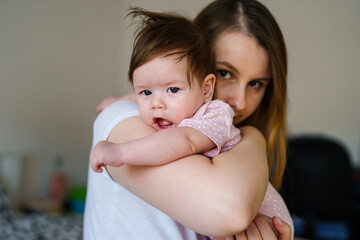 Caucasian woman mother holding her baby girl child daughter at home in room in summer day - parenthood day family concept real people front view