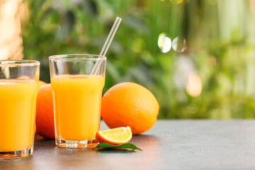 Glasses of tasty orange juice on table outdoors, closeup