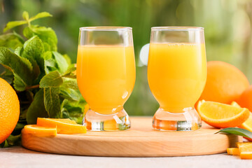Glasses of tasty orange juice on table outdoors, closeup