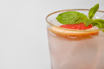 Glass of tasty grapefruit margarita on light background