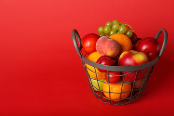 Basket with fresh fruits on color background