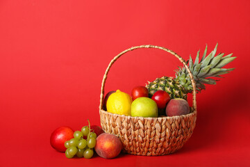 Basket with fresh fruits on color background
