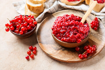 Bowl of red currant jam and berries on color background