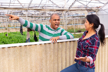 man and woman farm workers havilng conflict together at greenhouse farm