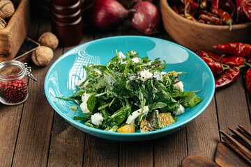 Green salad with oranges and mozzarella cheese on the wooden background