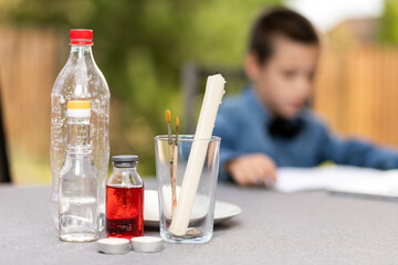 Close-up of ingredients for home chemical experiments with children: soda, vinegar, plastic bottle, candles, brushes, glass, alcohol